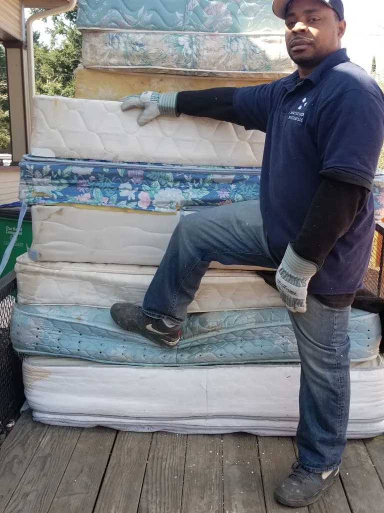 503 Clutter Busters junk removal technician posing in front of stacked up mattresses. Mattress Remval Mayhem!