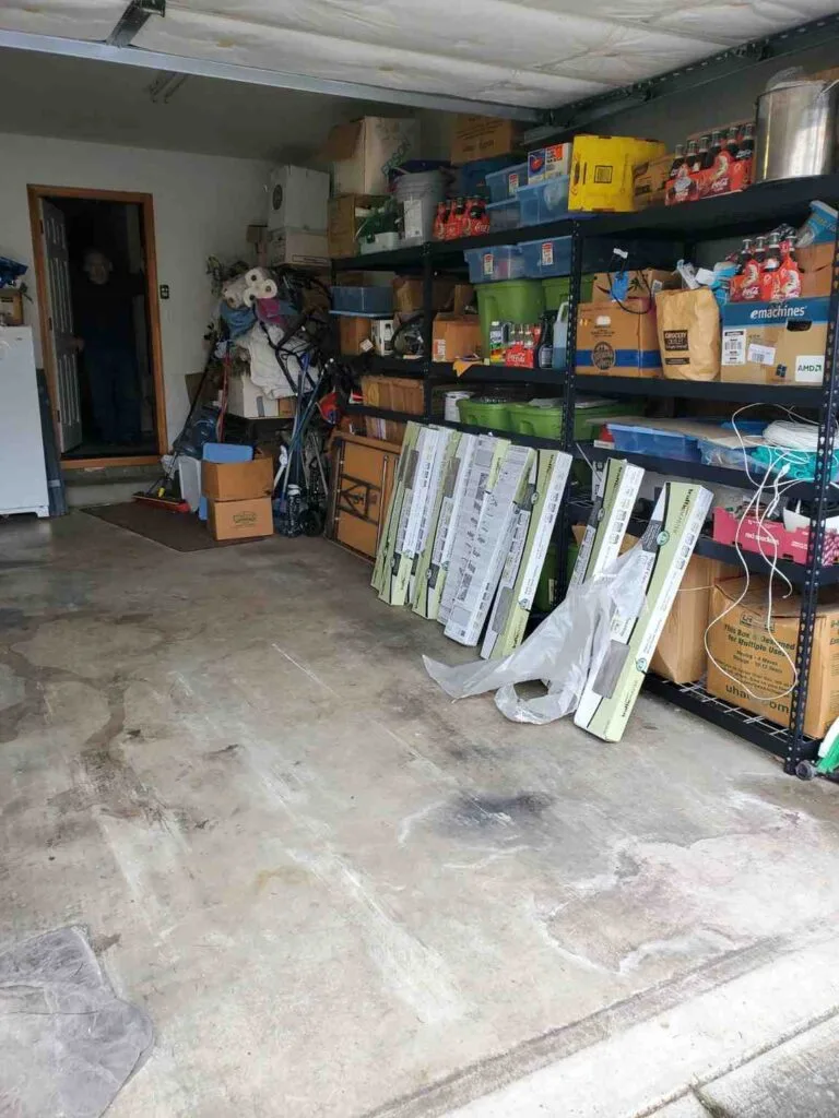 Clean and organized garage interior after professional debris removal service, showing empty floor space and organized shelving units.